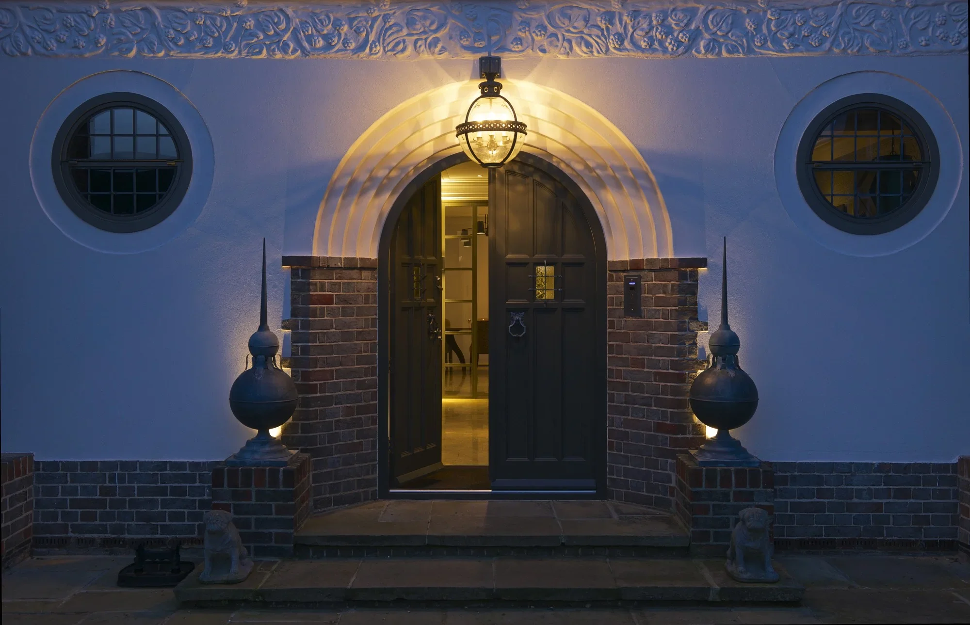 Blue-hour exterior with illuminated entrance and planting